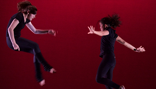 Two female students leaping in the air.